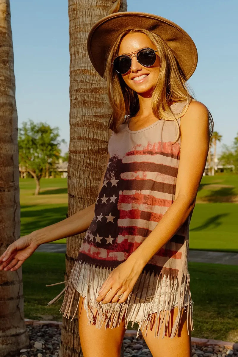Woman wearing an American flag fringe tank top outdoors, showcasing a trendy and patriotic summer style.
